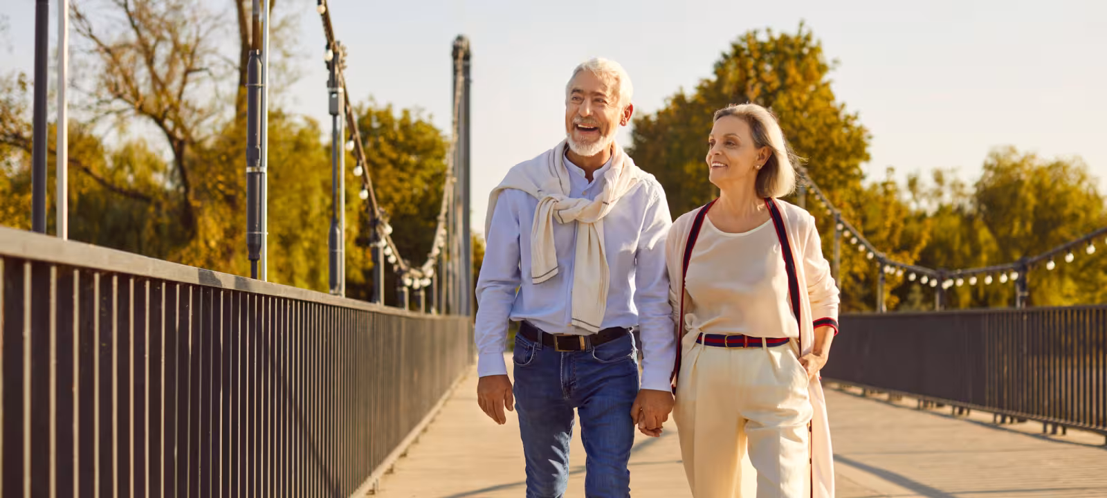 A happy retired couple walking along a sidewalk at golden hour