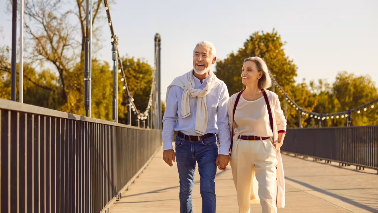A happy retired couple walking along a sidewalk at golden hour